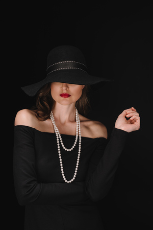 beautiful woman with eyes covered by black straw isolated on black backgroundの写真素材