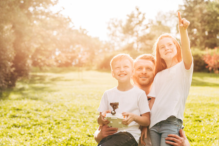 happy father with cute little kids playing with drone together at parkの写真素材