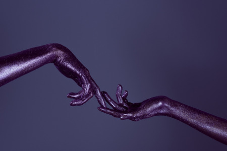 cropped view of girls hands in glitter touching each other with fingers, isolated on purple