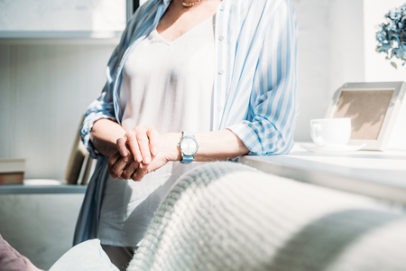 cropped shot of senior woman leaning on sofa at homeの写真素材