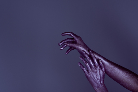 cropped view of tender hands in purple glitter, isolated on violetの写真素材