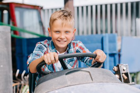 happy child riding agricultural vehicle and smiling at camera