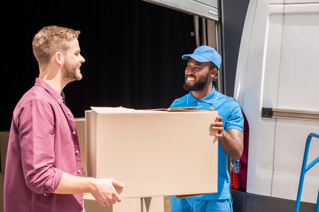 african american courier and caucasian client holding delivery box