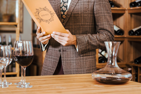 cropped shot of man in tweed jacket reading menu at wine storeの写真素材