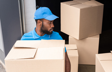 high angle view of african american delivery man holding box near storageの写真素材