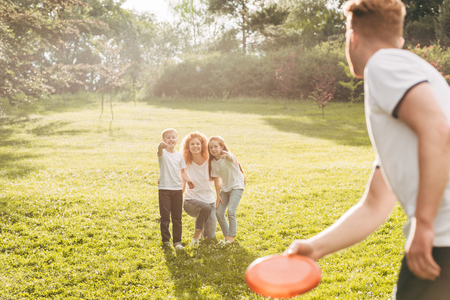 happy redhead family playing with flying disk at parkの写真素材