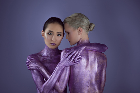 multiethnic naked girls in ultra violet glitter hugging together, isolated on purpleの写真素材