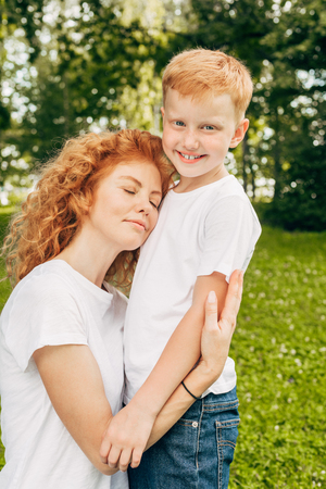 happy young mother hugging adorable little son in parkの写真素材