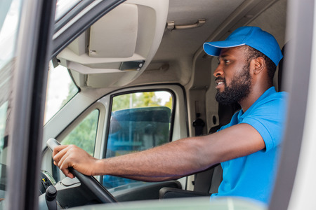 side view of african american delivery man driving van