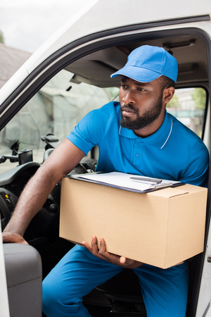 african american delivery man going out from car with boxの写真素材