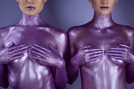 cropped view of nude girls in ultra violet glitter covering breasts, isolated on purpleの写真素材