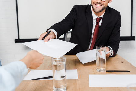 cropped shot of businessman passing blank papers to female colleague at officeの写真素材