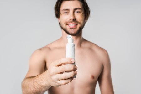 selective focus of cheerful shirtless man showing toothpaste isolated on greyの写真素材