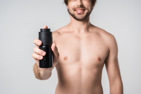 selective focus of shirtless man with male deodorant isolated on greyの写真素材