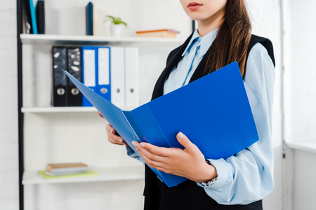 cropped shot of young businesswoman with folder of documents at modern officeの写真素材