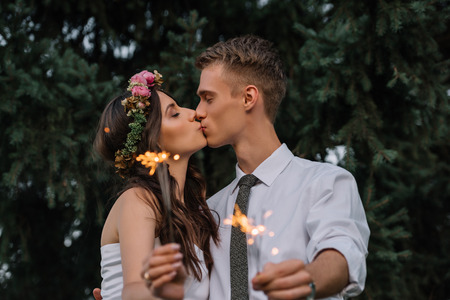 beautiful happy young wedding couple kissing and holding sparklersの写真素材