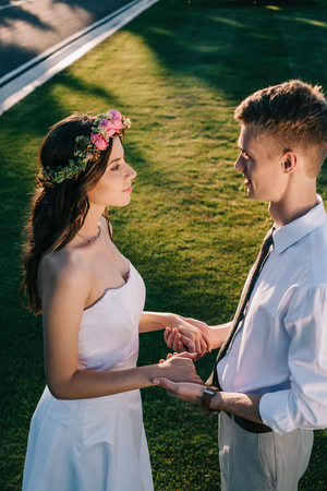 high angle view of beautiful young wedding couple holding hands and looking at each other in parkの写真素材