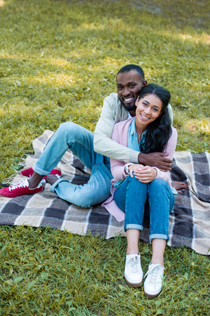 high angle view of smiling african american boyfriend hugging girlfriend in parkの写真素材