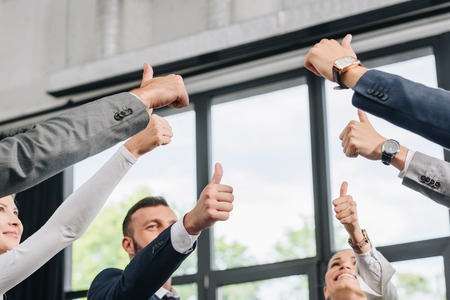 low angle view of businesspeople showing thumbs up in hubの写真素材