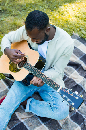 high angle view of african american man playing acoustic guitar in parkの写真素材
