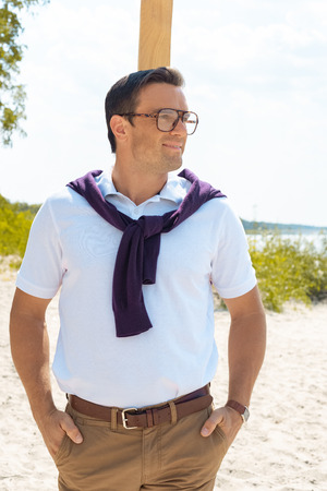 portrait of smiling man in eyeglasses on sandy beachの写真素材