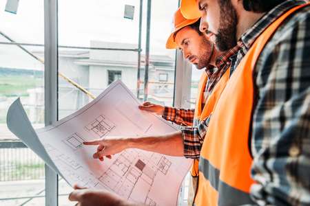 thoughtful builders working with blueprint at construction site