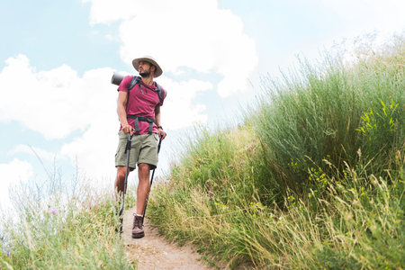 hiker in hat with backpack and tourist mat walking on pathの写真素材