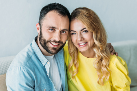 beautiful couple embracing and looking at camera at homeの写真素材