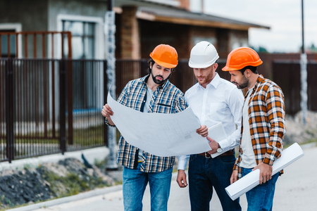group of architects standing on building street with blueprintsの写真素材
