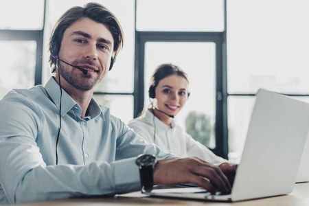 male and female call center managers working together at modern office and looking at cameraの写真素材
