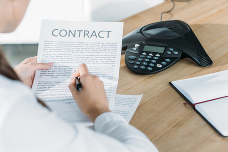 cropped shot of businesswoman reading contract at officeの写真素材