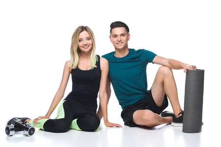 fit young couple in sportswear sitting on floor isolated on white