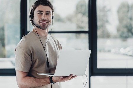 handsome young support hotline worker with laptop and headphonesの写真素材