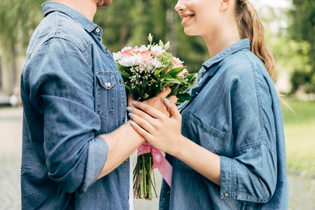 cropped shot of young couple holding flower bouquet at parkの写真素材