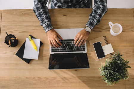 cropped shot of businessman working with laptop at workplace