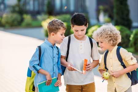 group of adorable schoolboys looking at notebook togetherの写真素材