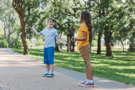 cute happy children playing with skipping ropes in parkの写真素材