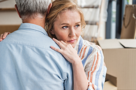 cropped shot of grey hair man hugging pensive wife while moving homeの写真素材