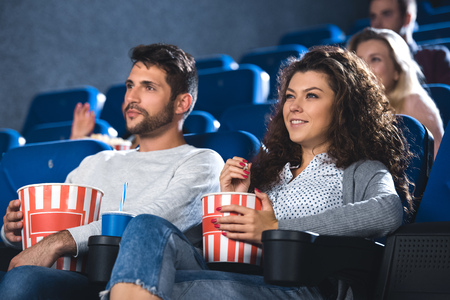 couple with popcorn and soda drink watching film together in cinemaの写真素材