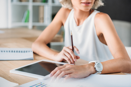 cropped image of businesswoman sitting at table with tablet in officeの写真素材