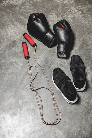 sporting shoes with jumping rope and boxing gloves on concrete surfaceの写真素材