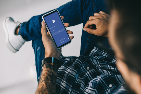 partial view of man using smartphone with facebook appのeditorial素材