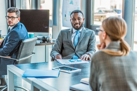 multicultural businesspeople talking at table in office