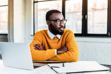 smiling african american businessman with crossed arms in officeの写真素材