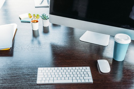 table with computer and cup of coffee in officeの写真素材