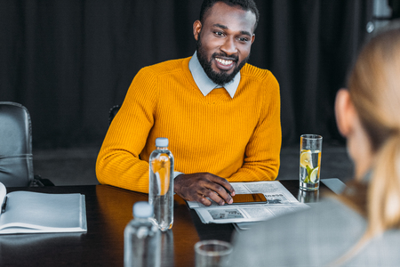 multicultural businessman and businesswoman looking at each other at table in officeの写真素材