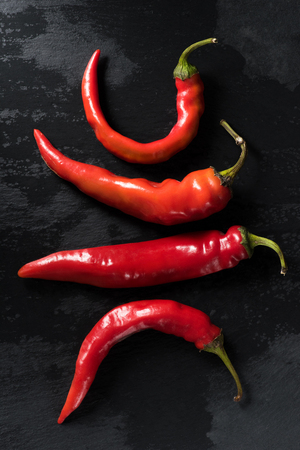 top view of raw red chili peppers on black tabletopの写真素材