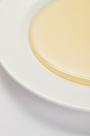 close up view of natural honey on plate on white surfaceの写真素材