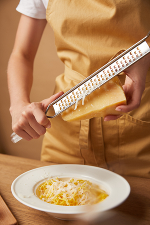 cropped shot of woman grating cheese onto spaghettiの写真素材