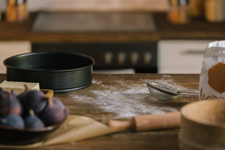 close-up shot of fig pie ingredients on wooden table covered with flour